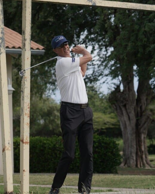 Portrait of Ed van Kampen following through on a golf swing at the Curaçao Golf & Squash Club